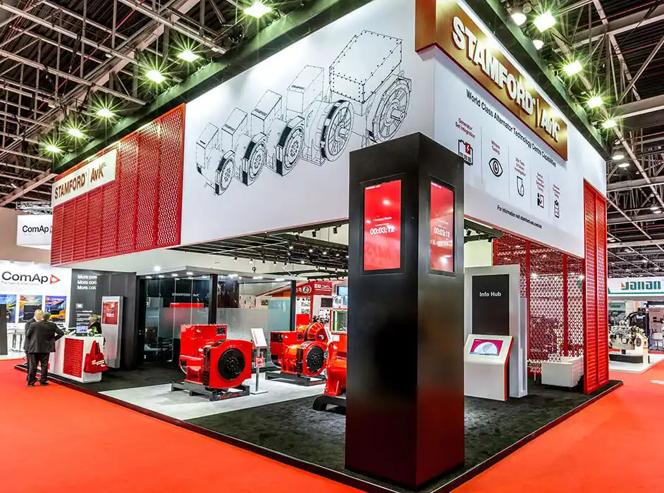 A large bespoke exhibition stand for Cummins Generators at the Middle East Electricity show, featuring red, black and white branding throughout the stand build elements. Physical products are displayed through the stand, complemented with digital screens to provide more information.